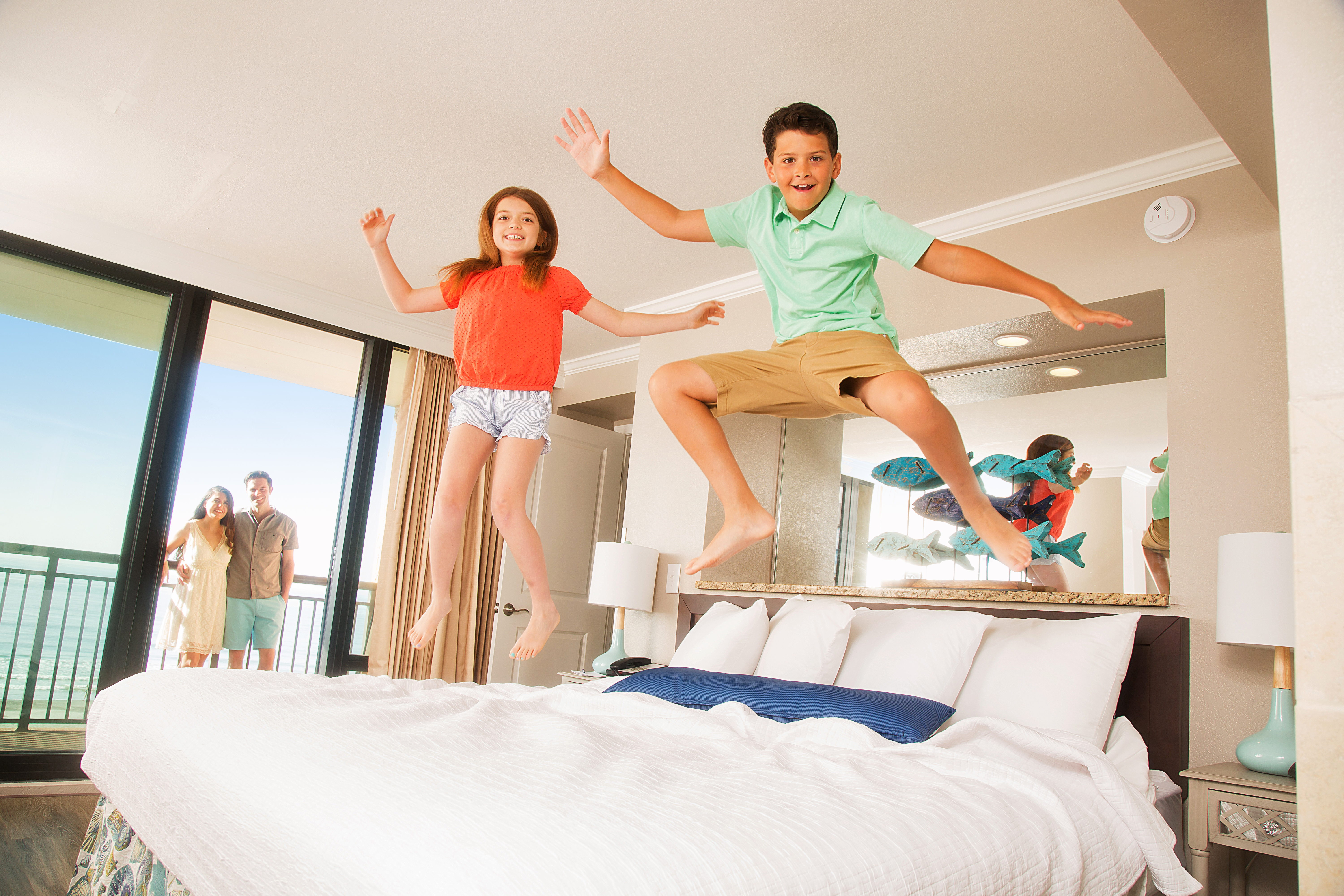 kids jumping on bed in room at caravelle resort