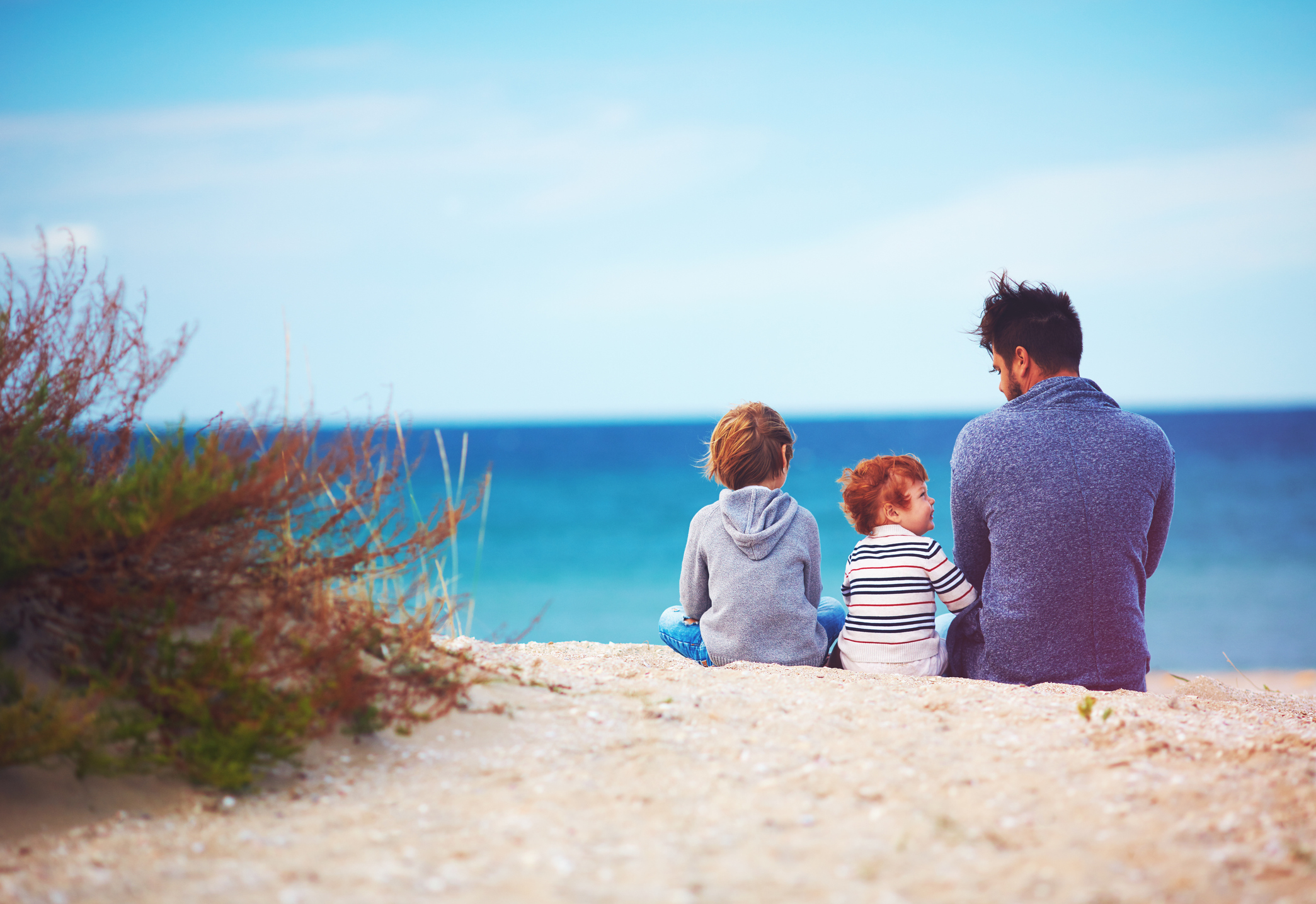 family sitting on the beach near the dunes