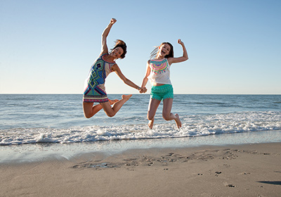 Mom and daughter jumping on the beach