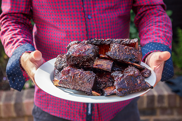 Man holding a plate of barbeque. 